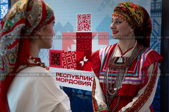 Девушки в традиционном национальном наряде стоит у стенда Республики Мордовия во время проведения выставки-форума "Россия" на ВДНХ в городе Москве, Россия (2024 год). Редакционное фото, фотограф Николай Винокуров / Фотобанк Лори