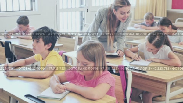 Diligent tweens studying in classroom, listening to lecturer and writing in notebooks. Стоковое видео, видеограф Яков Филимонов / Фотобанк Лори