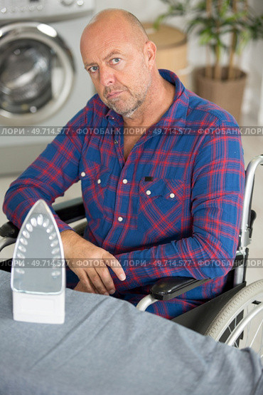 disabled man on wheelchair ironing clothing. Стоковое фото, агентство Ingram Publishing / Фотобанк Лори