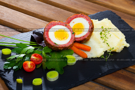 Dish scotch egg with tomatoes, mashed potatoes and greens, traditional Scottish cuisine. Стоковое фото, фотограф Яков Филимонов / Фотобанк Лори