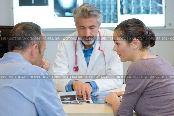 Doctor looking at xrays with couple. Стоковое фото, агентство Ingram Publishing / Фотобанк Лори