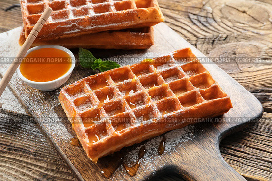Доска с вкусными бельгийскими вафлями и медом на деревянном фоне, крупным планом. Стоковое фото, фотограф Pixel_shot / Фотобанк Лори