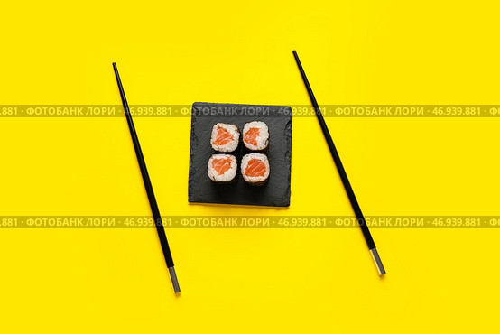 Доска с вкусными роллами маки из лосося и палочками для еды на цветном фоне. Стоковое фото, фотограф Pixel_shot / Фотобанк Лори