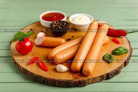 Доска вкусных колбасок с базиликом и чили на зеленом деревянном фоне. Стоковое фото, фотограф Pixel_shot / Фотобанк Лори