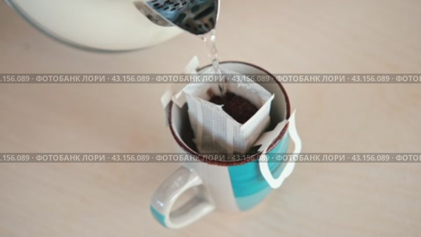 Drip bag fresh coffee. Pouring hot water into blue cup with drip coffee bag. Instant freshly brewed cup of ground coffee. Coffee Trend. Quick way to brew using paper filter. The process of brewing. Стоковое видео, видеограф Марина Демидюк / Фотобанк Лори