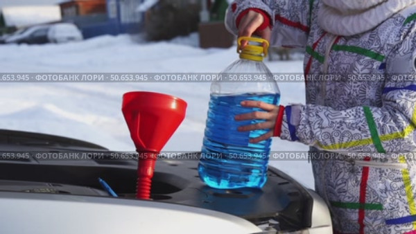 Driver pours glass fluid into car in winter. Стоковое видео, видеограф Igor Skripachev / Фотобанк Лори