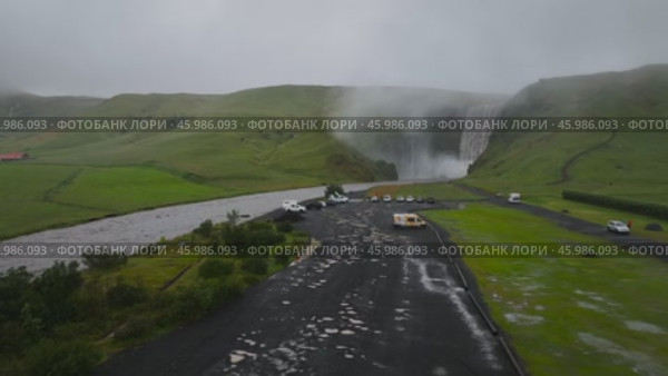Дрон отдаляется от водопада Скогафосс в Исландии, пролетает над парковкой рядом с водопадом, и в конце его атакуют птицы, придавая спокойной исландской сцене неожиданный поворот. Стоковое видео, видеограф Yana Veretennikova / Фотобанк Лори
