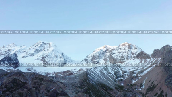 Drone flying along snow covered white mountain glacier in sunny autumn sunrise. Стоковое видео, видеограф Кирилл Трифонов / Фотобанк Лори