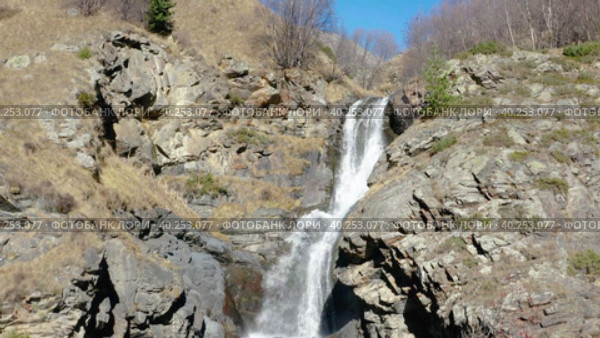 Drone flying down along rapid stream of mountain waterfall in sunny autumn day. Стоковое видео, видеограф Кирилл Трифонов / Фотобанк Лори