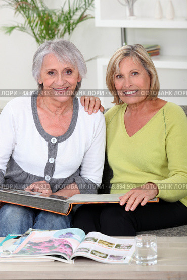 duo of grandmothers skimming through album. Стоковое фото, агентство Ingram Publishing / Фотобанк Лори