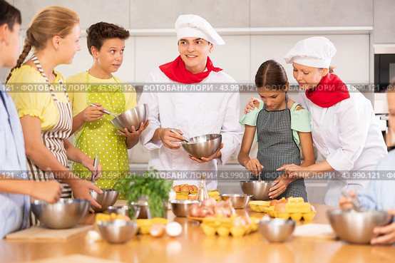 During cooking lesson, male cook tells children about culinary rules, woman assistant helps child. Стоковое фото, фотограф Яков Филимонов / Фотобанк Лори