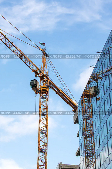 During the day, a crane is seen in front of a building under construction. Стоковое фото, фотограф Аксенова Вера / Фотобанк Лори