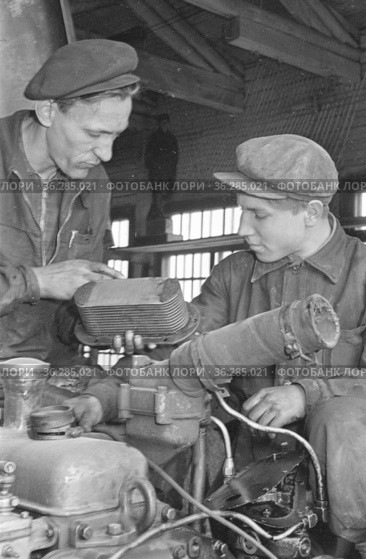 Два мастера Чульманской автобазы работают в ангаре, они меняют фильтры автомашины и проверяют транспорт на наличие поломок, Якутия, май 1961 год. Редакционное фото, фотограф Варфоломей Тетерин / Фотобанк Лори