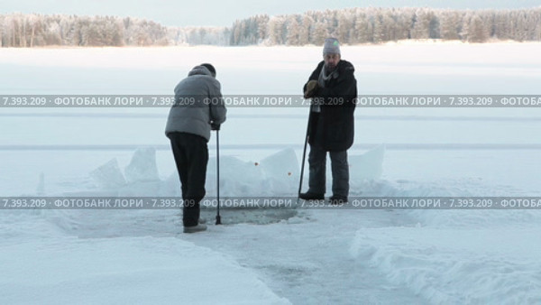Двое мужчин с ломом и топором рубят прорубь во льду зимнего озера. Стоковое видео, видеограф Кекяляйнен Андрей / Фотобанк Лори