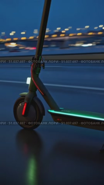 Dynamic Night Ride: A Close-Up of a Modern Electric Scooter Illuminated by Urban Lights, Showcasing Innovative Transportation in Action on a Rainy Evening. Стоковое AI-видео, аниматор Владимир Федоров / Фотобанк Лори