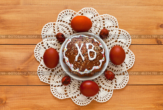 Easter composition with homemade tradition Easter cake on lace handmade napkin and painted red Easter eggs on wooden table. On Easter cake russian letters ХВ mean Christ is Risen. Flat lay, close-up. Стоковое фото, фотограф Виктория Катьянова / Фотобанк Лори