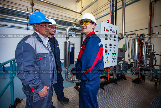 Ekibastuz, Kazakhstan - May 28, 2012. Explosive material production plant for coal quarry mining. Group of engineers talking. Equipment on background. Редакционное фото, фотограф Alexey Rezvykh / Фотобанк Лори