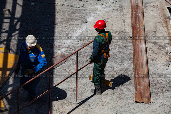 Ekibastuz, Pavlodar region, Kazakhstan - May 28, 2012: GRES-1 steam power station. Industrial climbers (builders) on metal roof. No face. Стоковое фото, фотограф Alexey Rezvykh / Фотобанк Лори