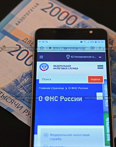 Экран смартфона сайтом Федеральной налоговой службы и российские деньги (2018 год). Редакционное фото, фотограф Цибаев Алексей / Фотобанк Лори