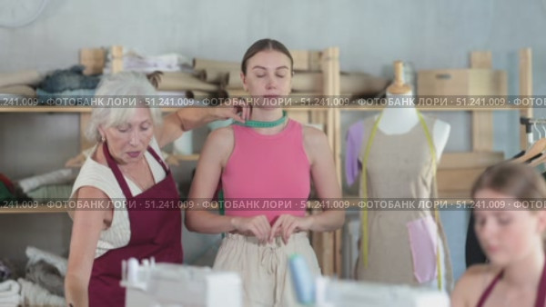 elderly dressmaker takes measurements from a woman in front of an experienced seamstress. Стоковое видео, видеограф Яков Филимонов / Фотобанк Лори