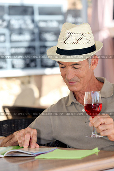 Elderly man drinking a glass of rose in a cafe. Стоковое фото, агентство Ingram Publishing / Фотобанк Лори
