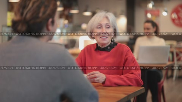 Elderly woman meets a man in a cafe. Conversation over a cup of coffee. Стоковое видео, видеограф Яков Филимонов / Фотобанк Лори