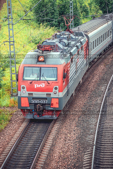 Electric train, Russian Railways, A modern red passenger train is seen traveling on a railway surrounded by lush greenery Krasnoyarsk, Russia, July 27, 2024. Редакционное фото, фотограф Владимир Разгуляев / Фотобанк Лори