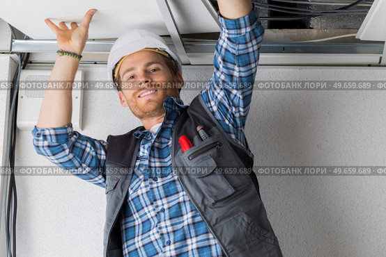 electrical worker wiring in ceiling. Стоковое фото, агентство Ingram Publishing / Фотобанк Лори