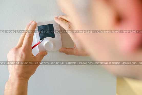 Electrician fitting a thermostat. Стоковое фото, агентство Ingram Publishing / Фотобанк Лори