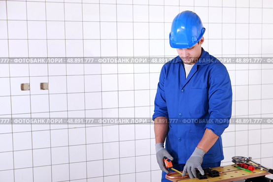 electrician is measuring copper wire length on a workbench. Стоковое фото, агентство Ingram Publishing / Фотобанк Лори
