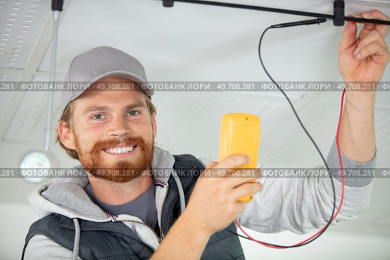 electrician using a multimeter to test spotlight connections. Стоковое фото, агентство Ingram Publishing / Фотобанк Лори