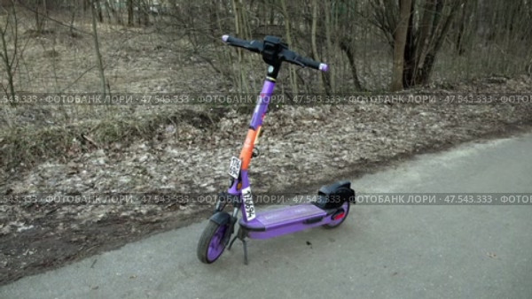 Электросамокат стоит на дорожке в лесу. Март. An electric scooter stands on a path in the forest. March. Редакционное видео, видеограф Горшков Александр / Фотобанк Лори