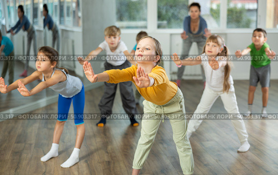 Energetic children practicing modern vigorous movements in dance class. Стоковое фото, фотограф Яков Филимонов / Фотобанк Лори