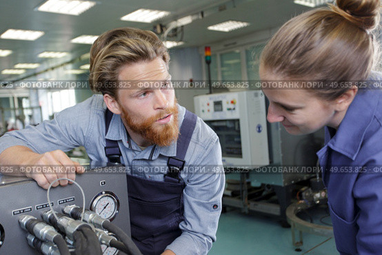engineer helping female apprentice in factory. Стоковое фото, агентство Ingram Publishing / Фотобанк Лори