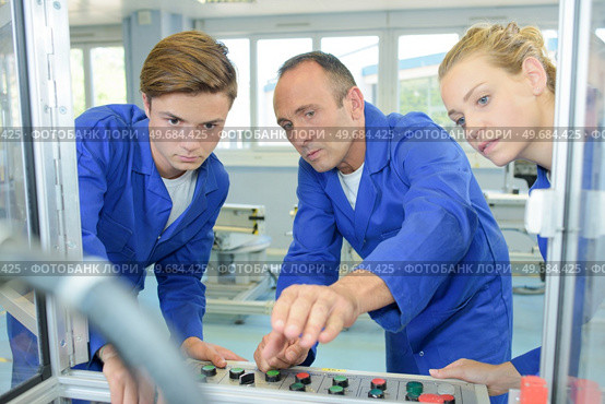 engineer showing apprentices how to operate machine. Стоковое фото, агентство Ingram Publishing / Фотобанк Лори