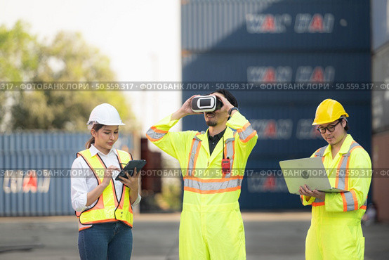 Engineers and laborers utilize VR headsets to control work in a container warehouse. Стоковое фото, агентство Ingram Publishing / Фотобанк Лори