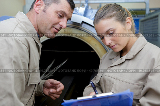 engineers by machinery woman taking notes. Стоковое фото, агентство Ingram Publishing / Фотобанк Лори