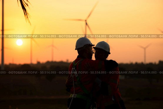 Engineers working on wind farms for renewable energy are responsible for maintaining large wind turbines. Returning from work during while the evening sun shines a beautiful golden light upon both of. Стоковое фото, агентство Ingram Publishing / Фотобанк Лори