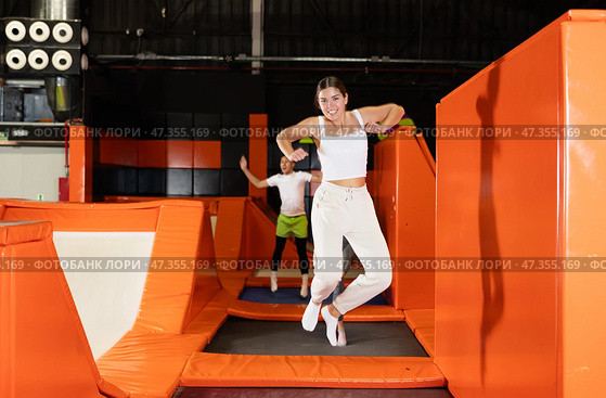 Excited young girl jumping at indoor trampoline center. Стоковое фото, фотограф Яков Филимонов / Фотобанк Лори