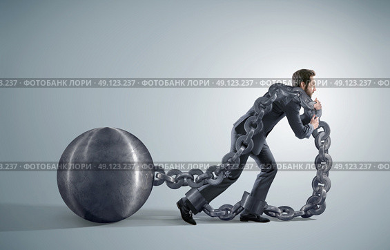 Exhausted businessman dragging heavy chains. Стоковое фото, агентство Ingram Publishing / Фотобанк Лори