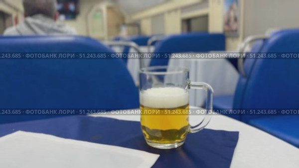Experience the Charming Beer Scene in a Cozy and Inviting Dining Car with Friends and Good Company. A refreshing and cold beer sits atop a table in a cozy and comfortable dining car setting, evoking pure relaxation. Стоковое видео, видеограф worker / Фотобанк Лори