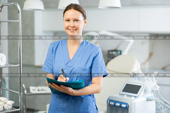 Experienced female doctor cosmetologist ready to receive clients in his office. In background Rf cosmetology machine. Стоковое фото, фотограф Яков Филимонов / Фотобанк Лори