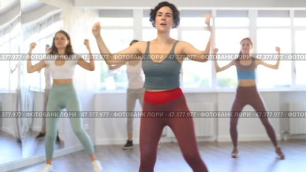 Expressive cheerful young Latina leading upbeat Zumba class for group of women in mirrored dance studio. Стоковое видео, видеограф Яков Филимонов / Фотобанк Лори