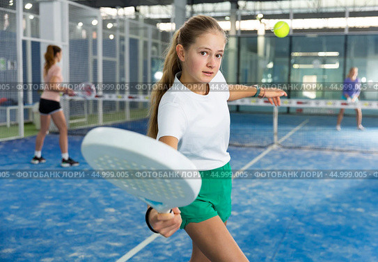 Expressive resolved fit teenage girl playing paddle ball friendly match on small closed court. Concept of competition emotions. Стоковое фото, фотограф Яков Филимонов / Фотобанк Лори