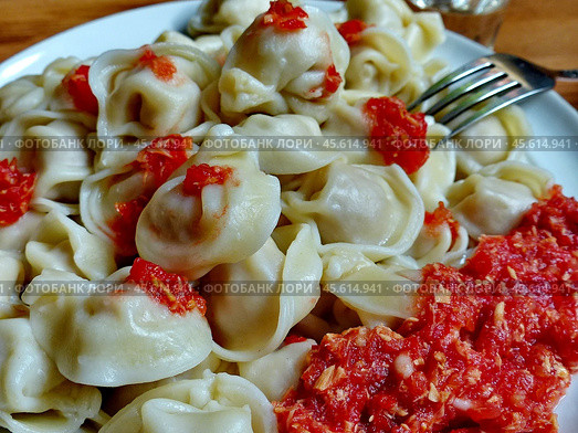 Ежегодно 18 февраля в некоторых странах отмечают вкуснейший гастрономических праздник, а именно - День пельменей. Сибирские пельмени ручной лепки и острая домашняя приправа "хреновина" из томата, хрена, чеснока. Пельмени — блюдо в виде отварных изделий из свежего теста с начинкой из рубленого мяса или рыбы. Стоковое фото, фотограф Сергей Елизарьев / Фотобанк Лори
