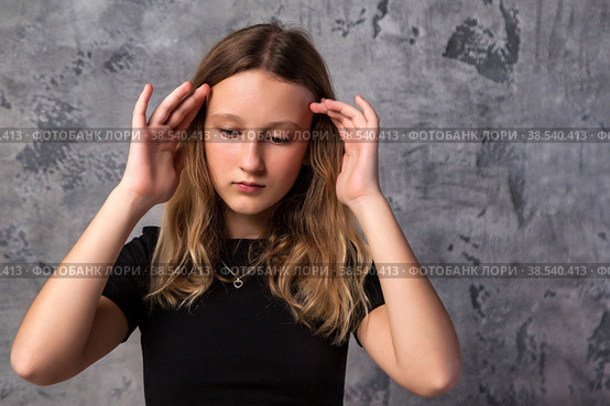 Face sorrowful sad teen girl in black clothes thinking looking down, at grey background. Pensive thoughtful teenager girl 12 years old posing in studio. Kid emotion concept. Copy text space. Стоковое фото, фотограф Aleksandr Golubev / Фотобанк Лори