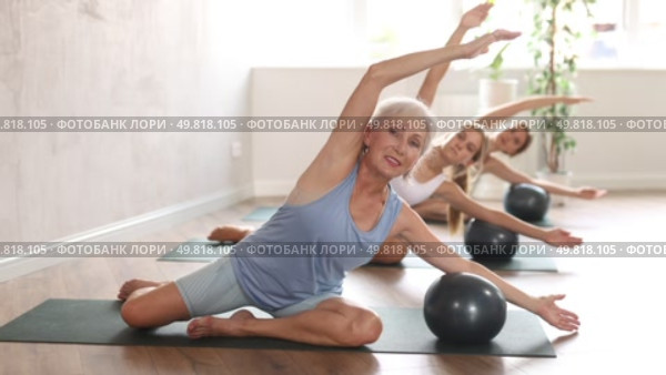 Family grandmother, mother and granddaughter perform fitness exercise sitting on floor with softball. Стоковое видео, видеограф Яков Филимонов / Фотобанк Лори