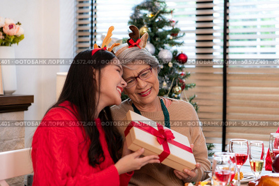 Family members are exchanging gifts with each other in the dinner time during the Christmas holiday at home. Стоковое фото, агентство Ingram Publishing / Фотобанк Лори