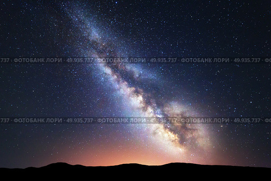 Fantastic night landscape with bright milky way. Milky Way. Fantastic night landscape with bright milky way, sky full of stars, yellow city light and mountains. Picturesque scene with our universe. Space background. Amazing astrophotography. Стоковое фото, агентство Ingram Publishing / Фотобанк Лори