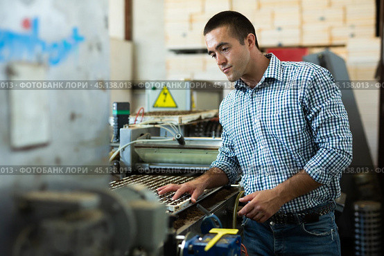 Farmer man working with automatic filling and seeding line for growing containerized seedlings of decorative plants in greenhouse. Стоковое фото, фотограф Яков Филимонов / Фотобанк Лори
